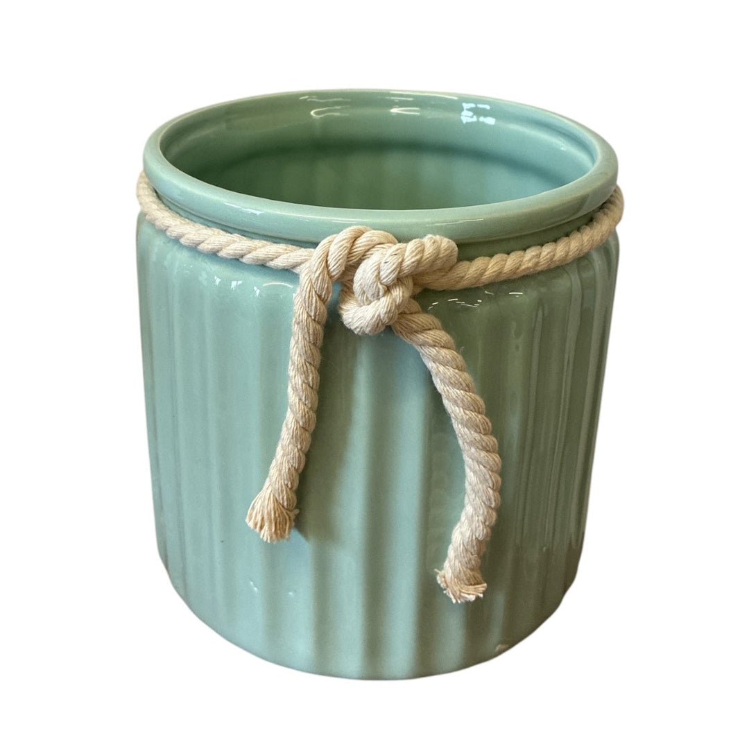 Green ceramic pot with a rope tied around it on a white background