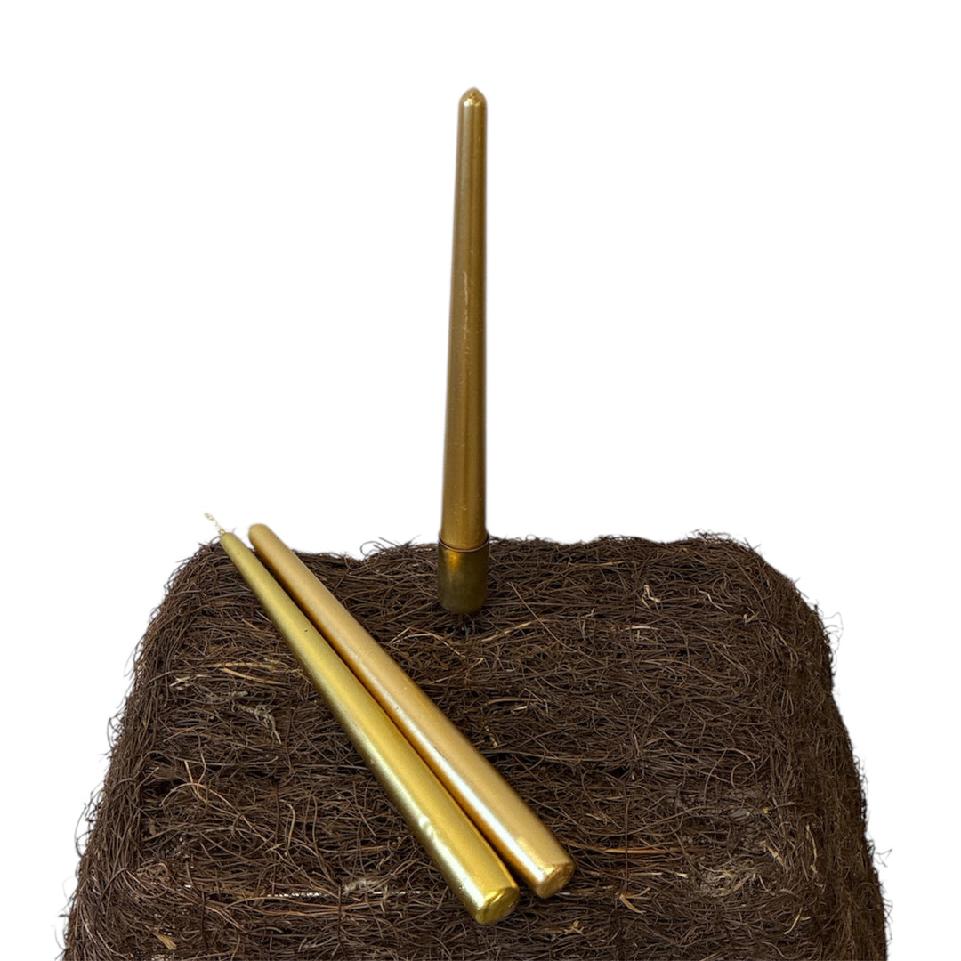 Coconut fiber block with three gold candles on a white background