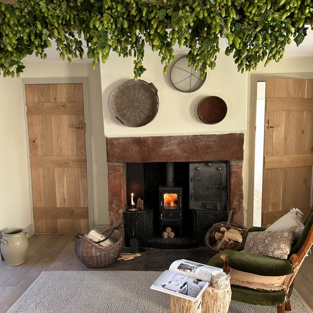 Decorative fresh hop bine garland styled across a stone fireplace mantelpiece