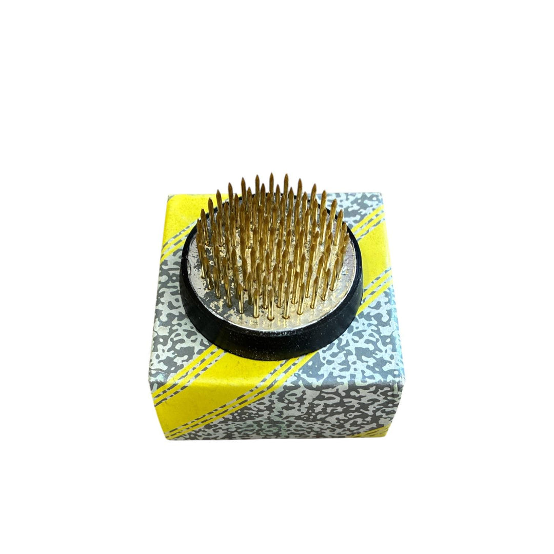 Cube-shaped container with a black base and gold pins on a white background