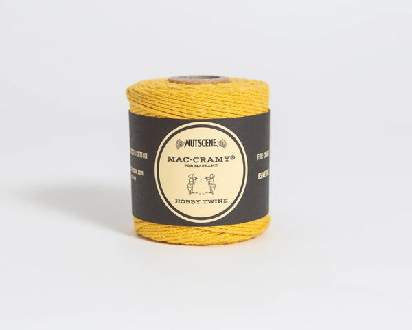 Spool of yellow twine with a label on a light gray background