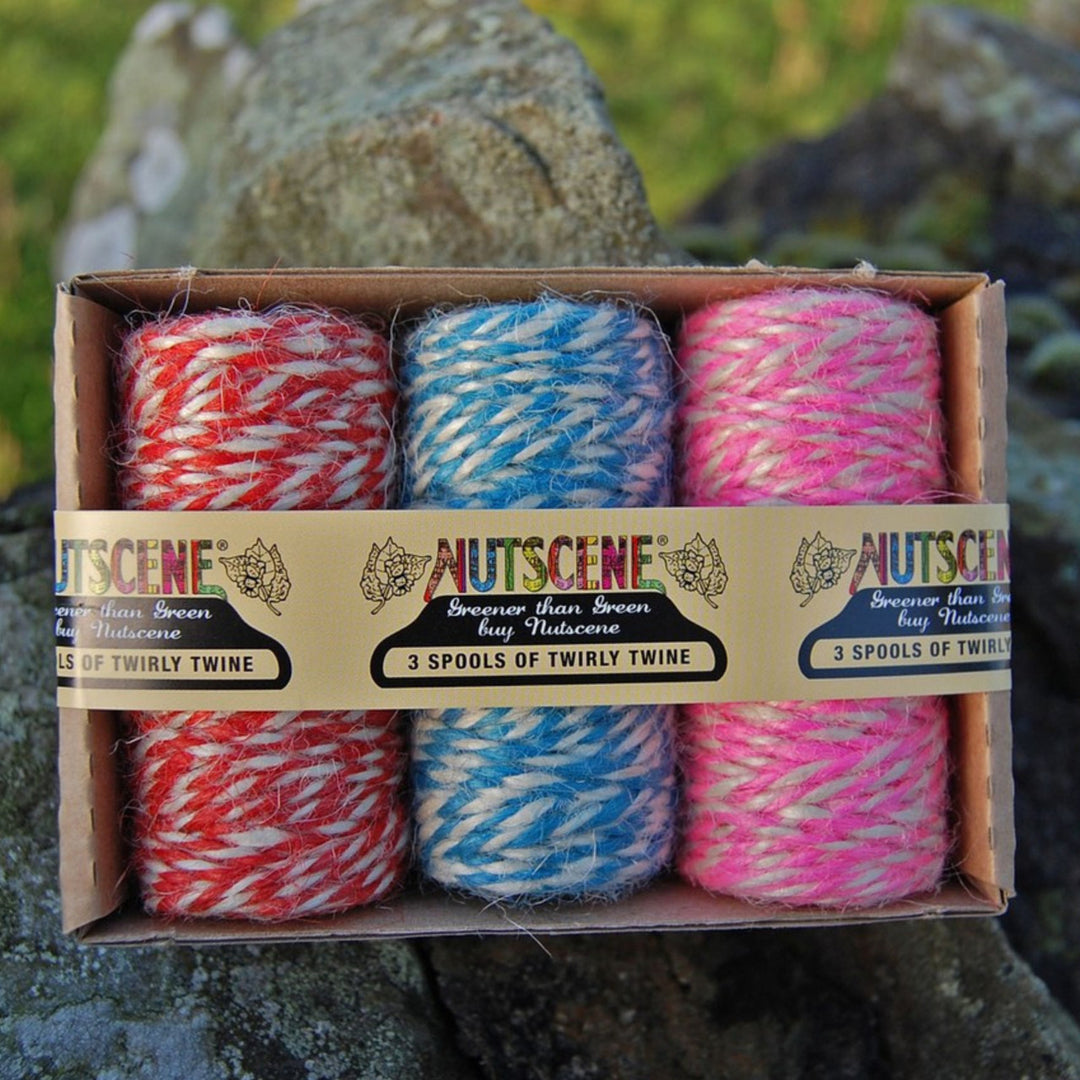 Three spools of Nutscene twirly twine in red, blue, and pink colors, displayed in a cardboard box with the brand label visible.
