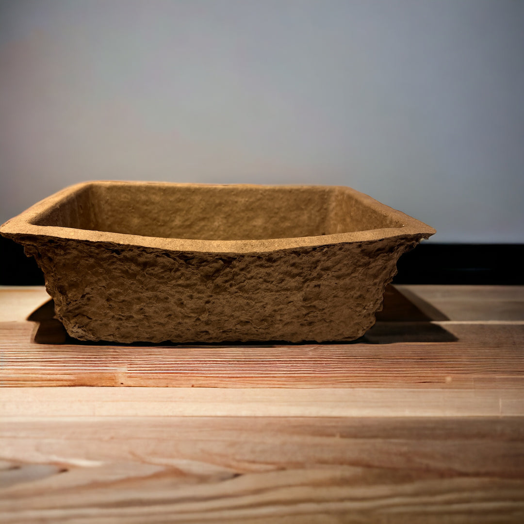 A single brown biodegradable brick trough on a wooden surface.