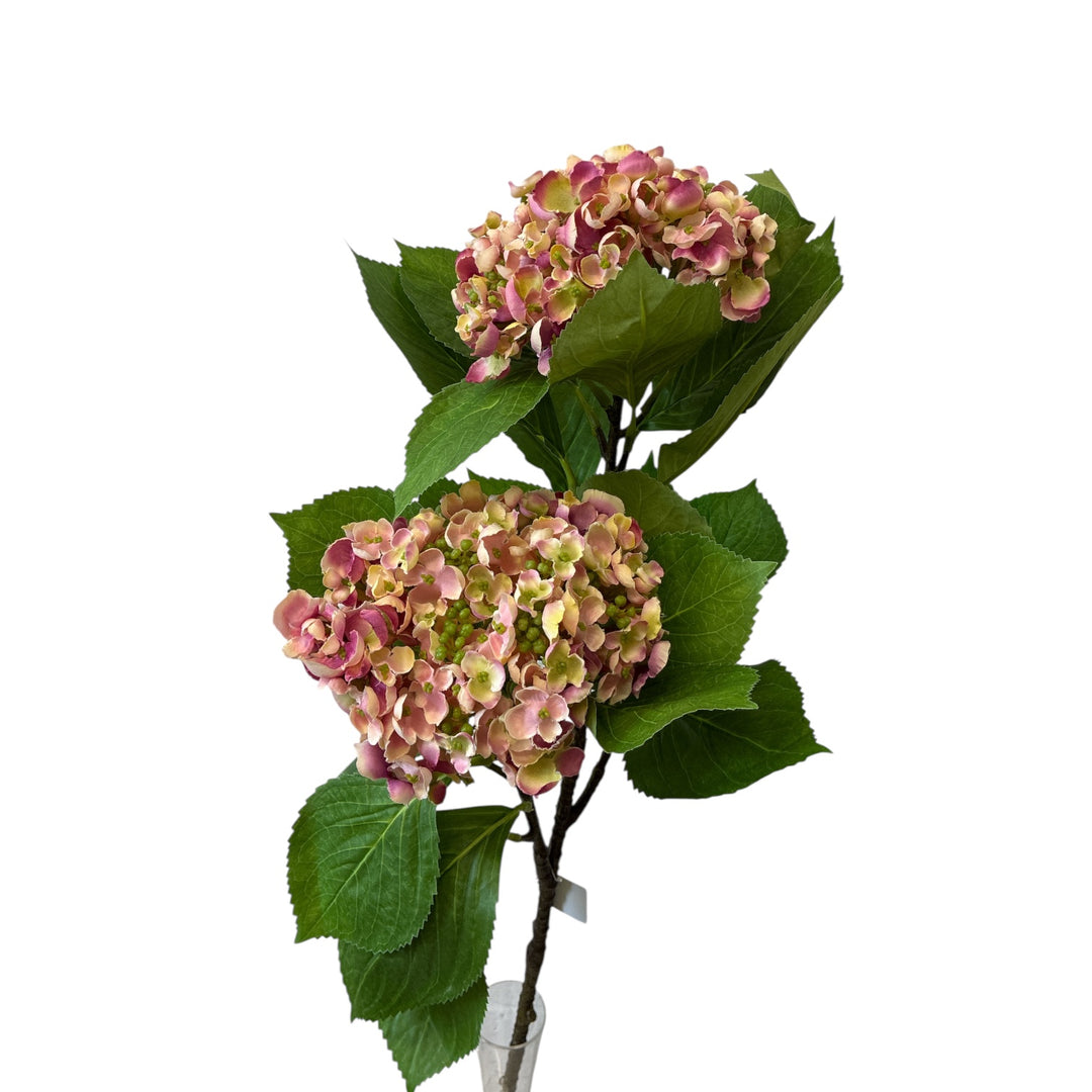 Artificial hydrangea branch with pink and green flowers on a white background
