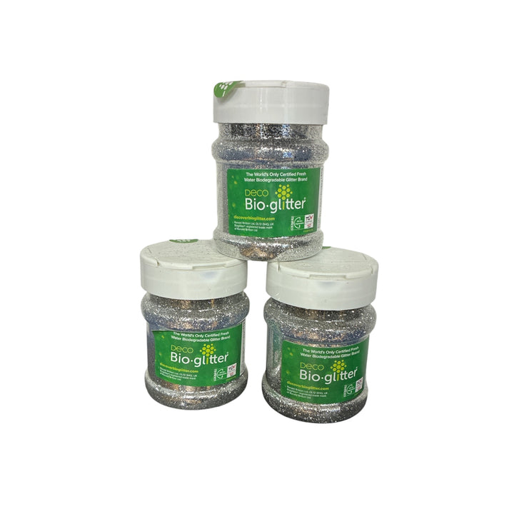 Three jars of Deco Silver Bio-glitter arranged in a pyramid on a plain white background. The jars are filled with silver glitter and feature green labels with white caps.