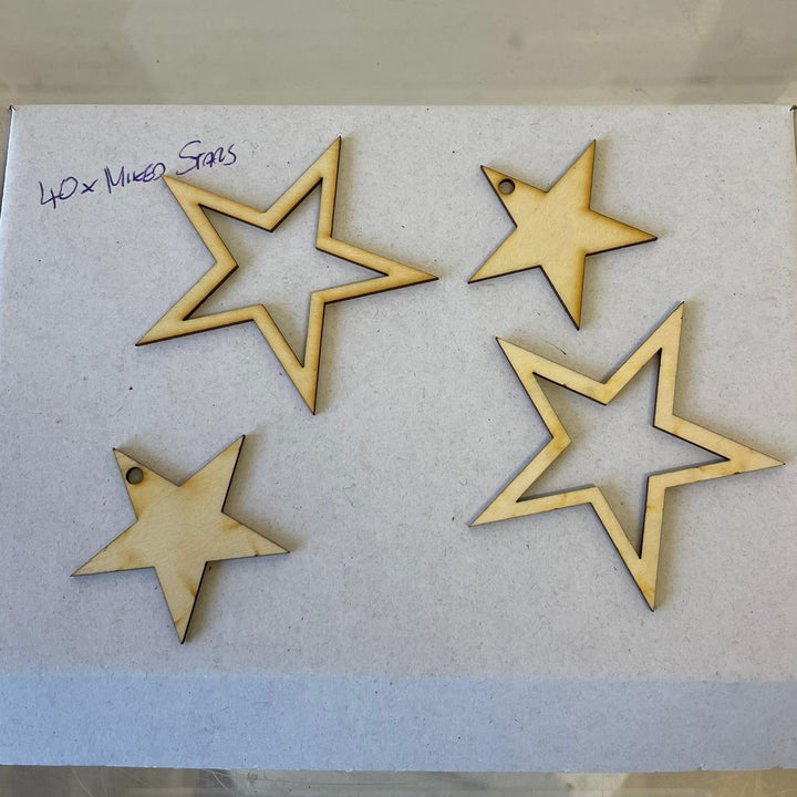 Flat lay of 5cm wooden stars laid flat on clean white paper, highlighting the smooth natural grain and clean precision-cut edges of the shapes.