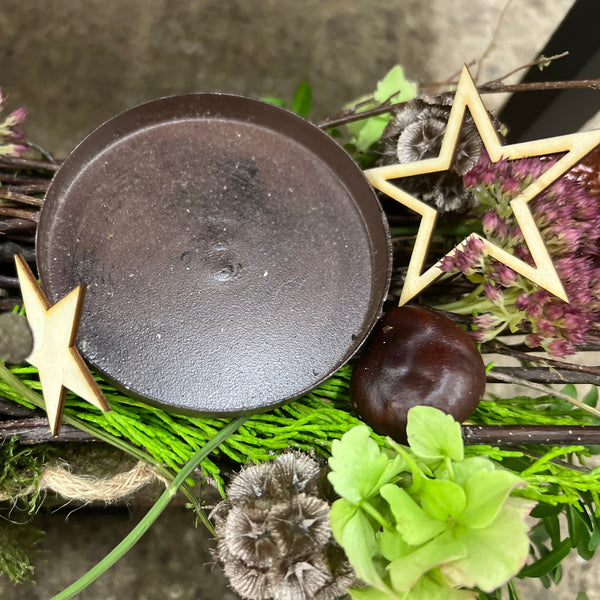 Lightweight natural wooden stars attached to a green festive Christmas wreath as a compostable, rustic decorative accent.