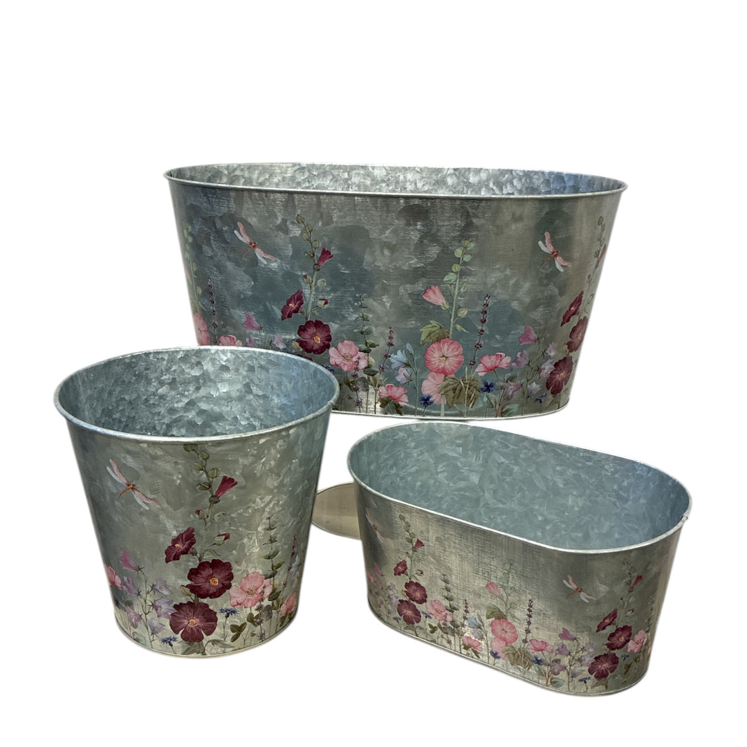 Set of three floral-patterned metal planters on a white background
