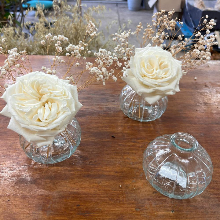 Romantic wedding tablescape decor featuring delicate stems of natural dried Gypsophila arranged in small glass bud vases alongside fresh white roses.