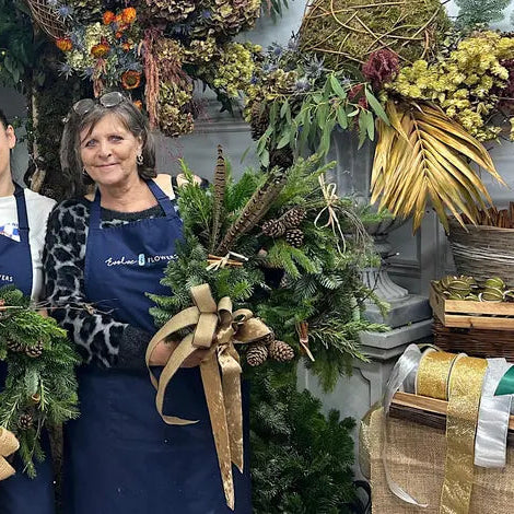 happy attendees proudly displaying their handmade festive door wreaths during a Christmas craft workshop at Evolve Flowers studio in Spalding, UK.