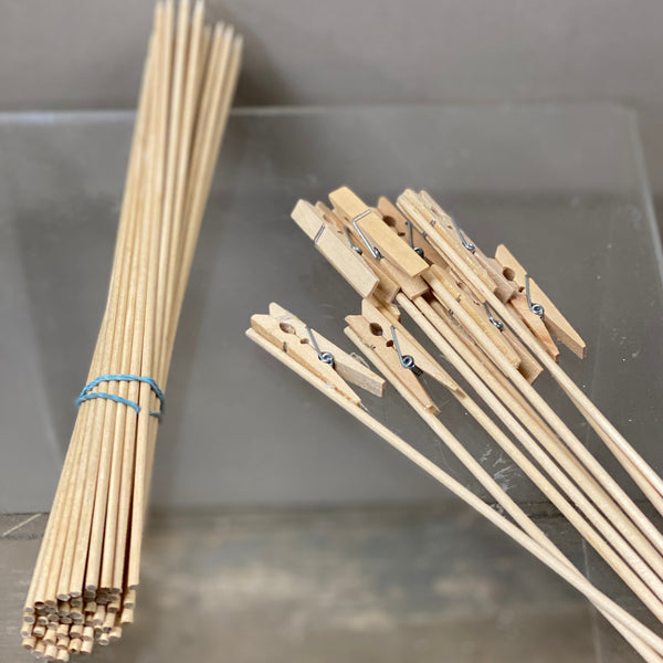 A bundle of wooden kebab sticks tied together with a blue band, displayed on a clear glass surface.