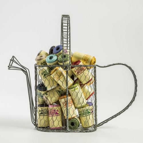 A collection of mini spools of twine in various colors, arranged inside a metal wire watering can-shaped container.